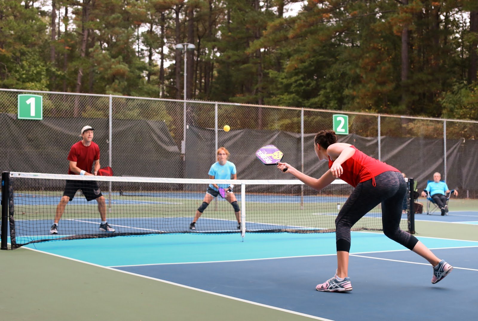 Doubles pickleball players on blue and green courts at Ephesus Park
