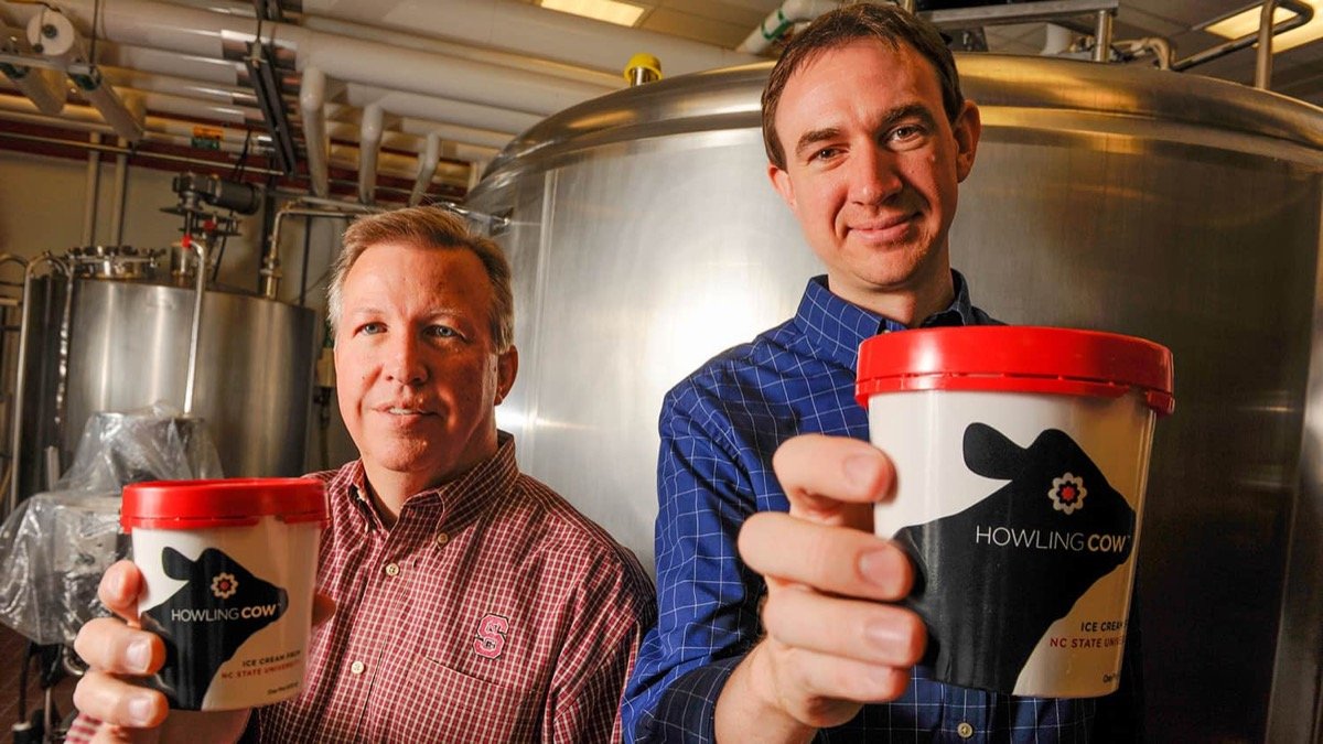 Two NC State dairy staff members holding containers of Howling Cow ice cream