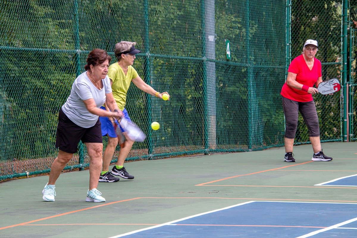 Older adults playing pickleball on outdoor courts in Apex