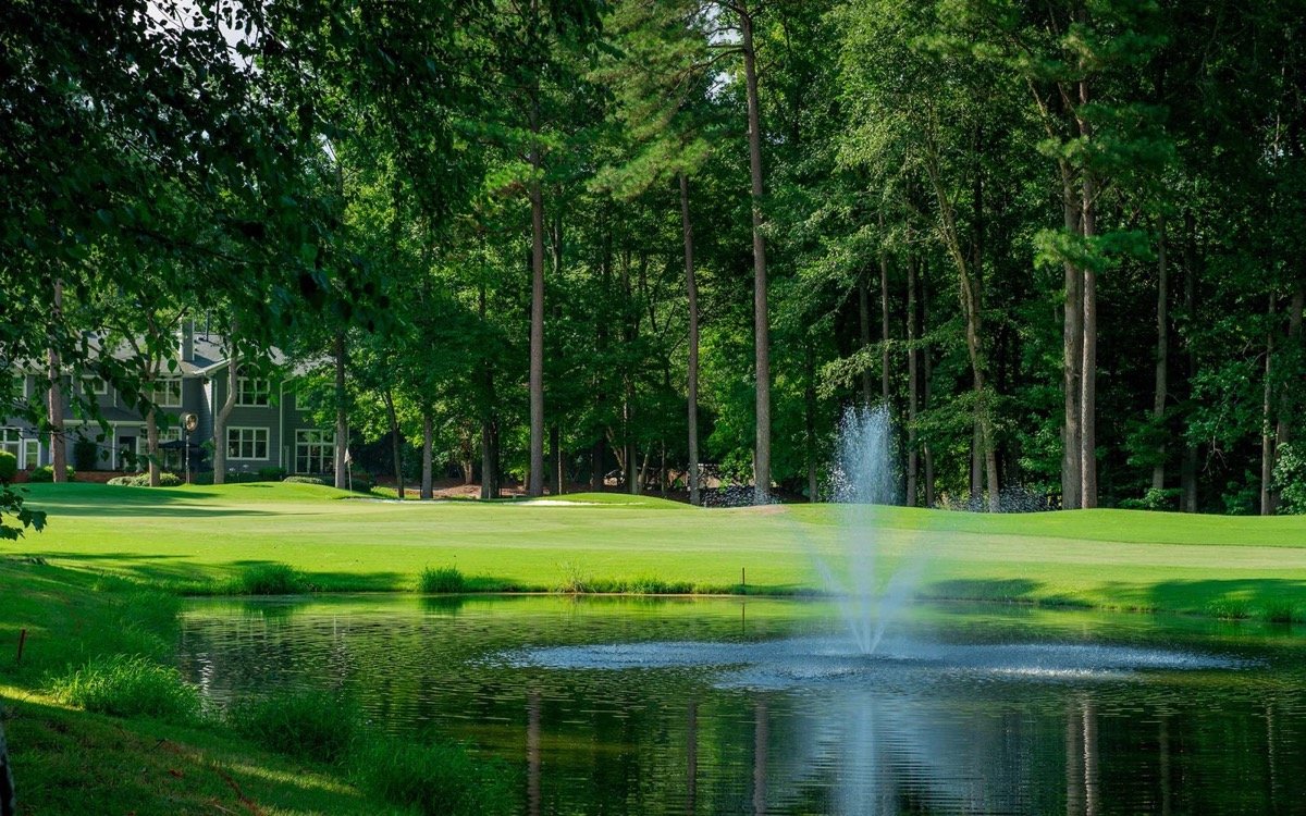 A green at Lochmere Golf Club beside a pond and fountain