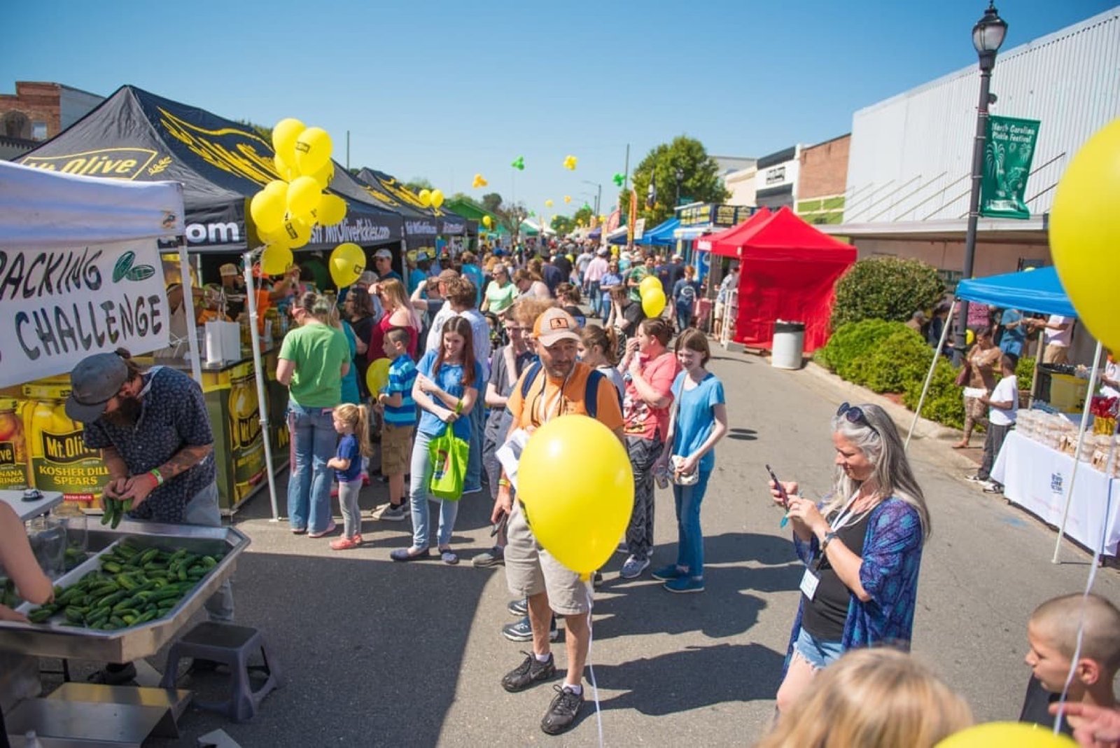 Crowd and pickle-themed booths at the North Carolina Pickle Festival in Mount Olive