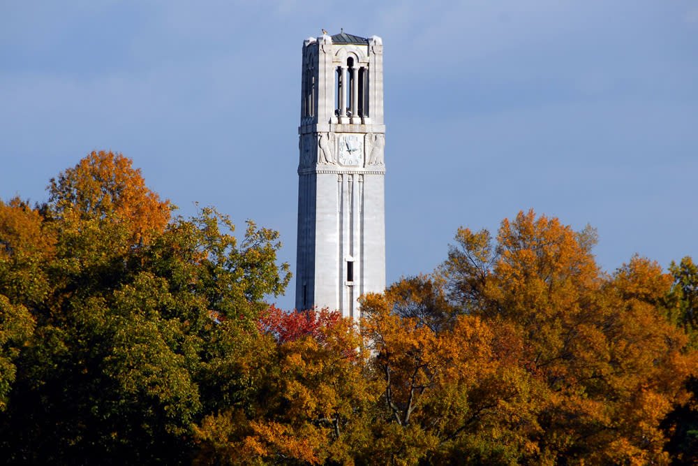 NC State Memorial Belltower rising above autumn trees in Raleigh