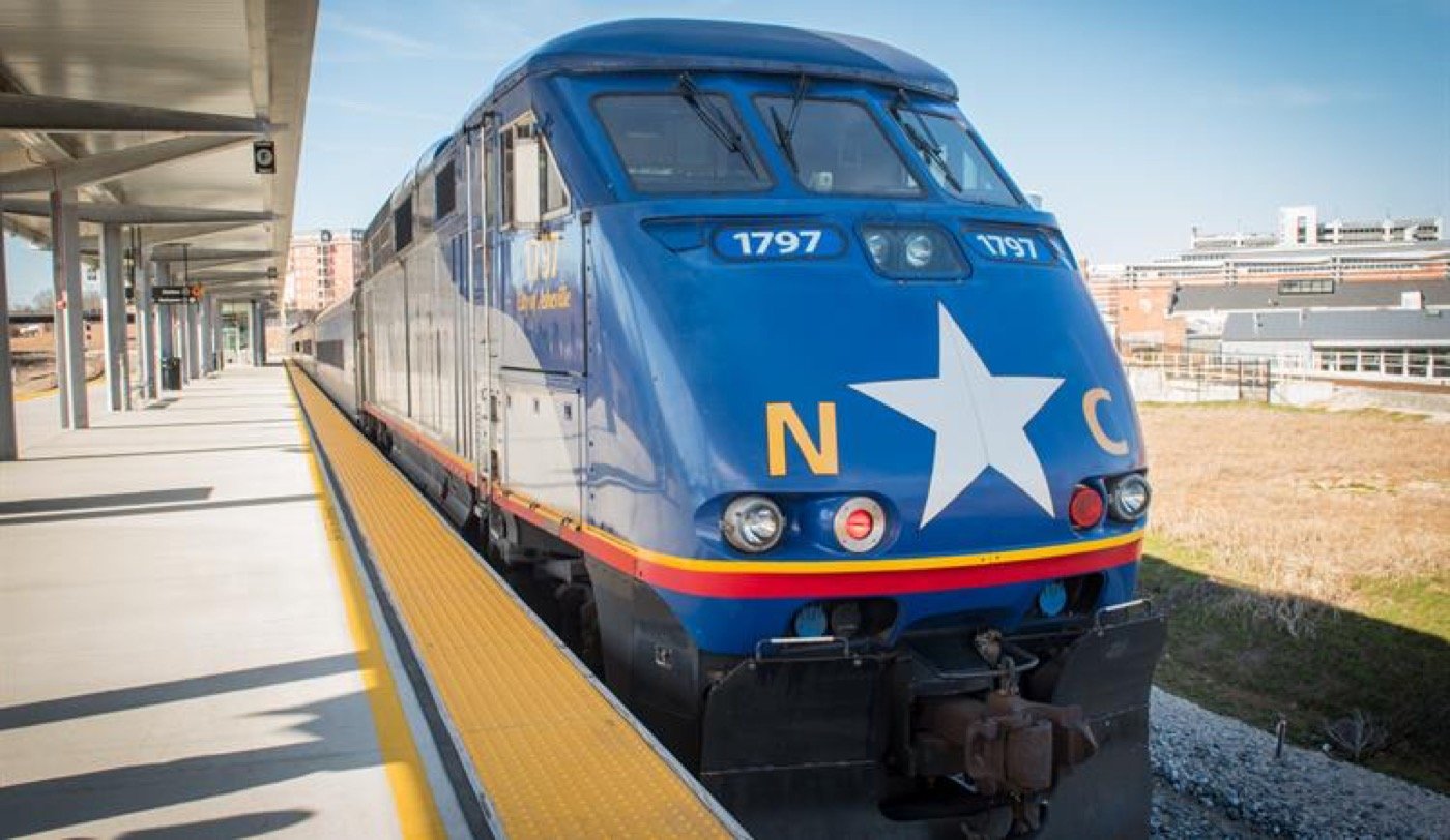 Blue NC By Train Piedmont locomotive beside a station platform
