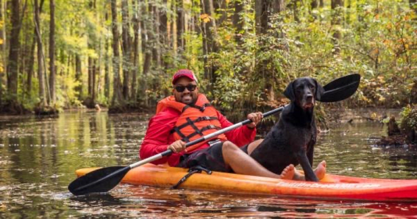 Kayaker and dog paddling among bald cypress trees at Robertson Millpond Preserve