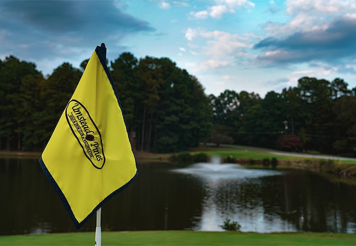 An Umstead Pines flag beside a pond and golf green