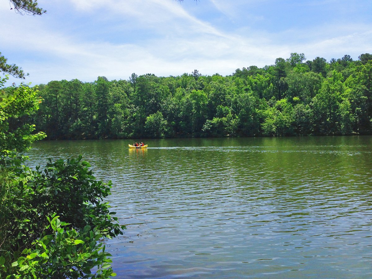 A small boat on Wake Forest Reservoir, with wooded banks beyond the water